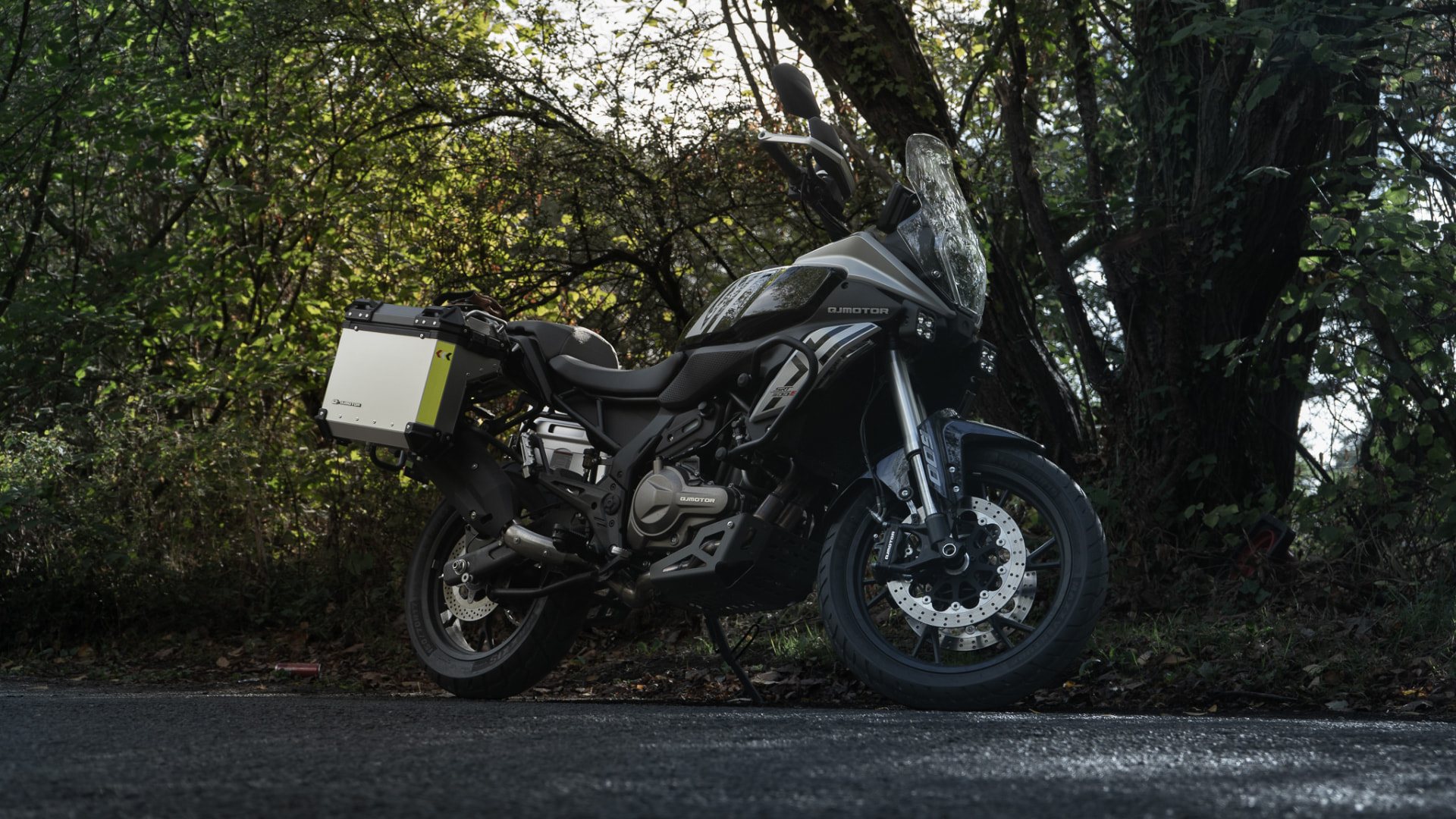 QJMotor SRT 600 S adventure motorcycle with panniers parked on a woodland lane