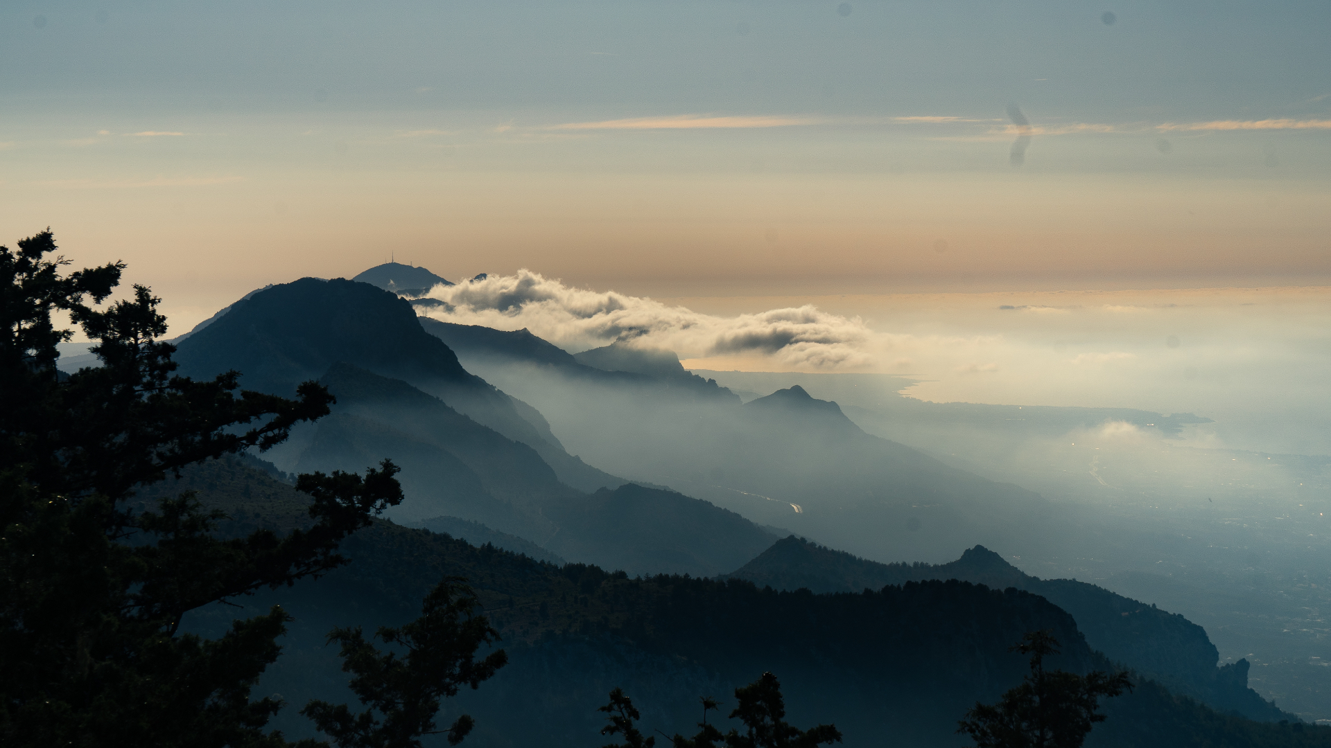 Layered mountain ridges of the Kyrenia range drifting through low cloud at dusk.