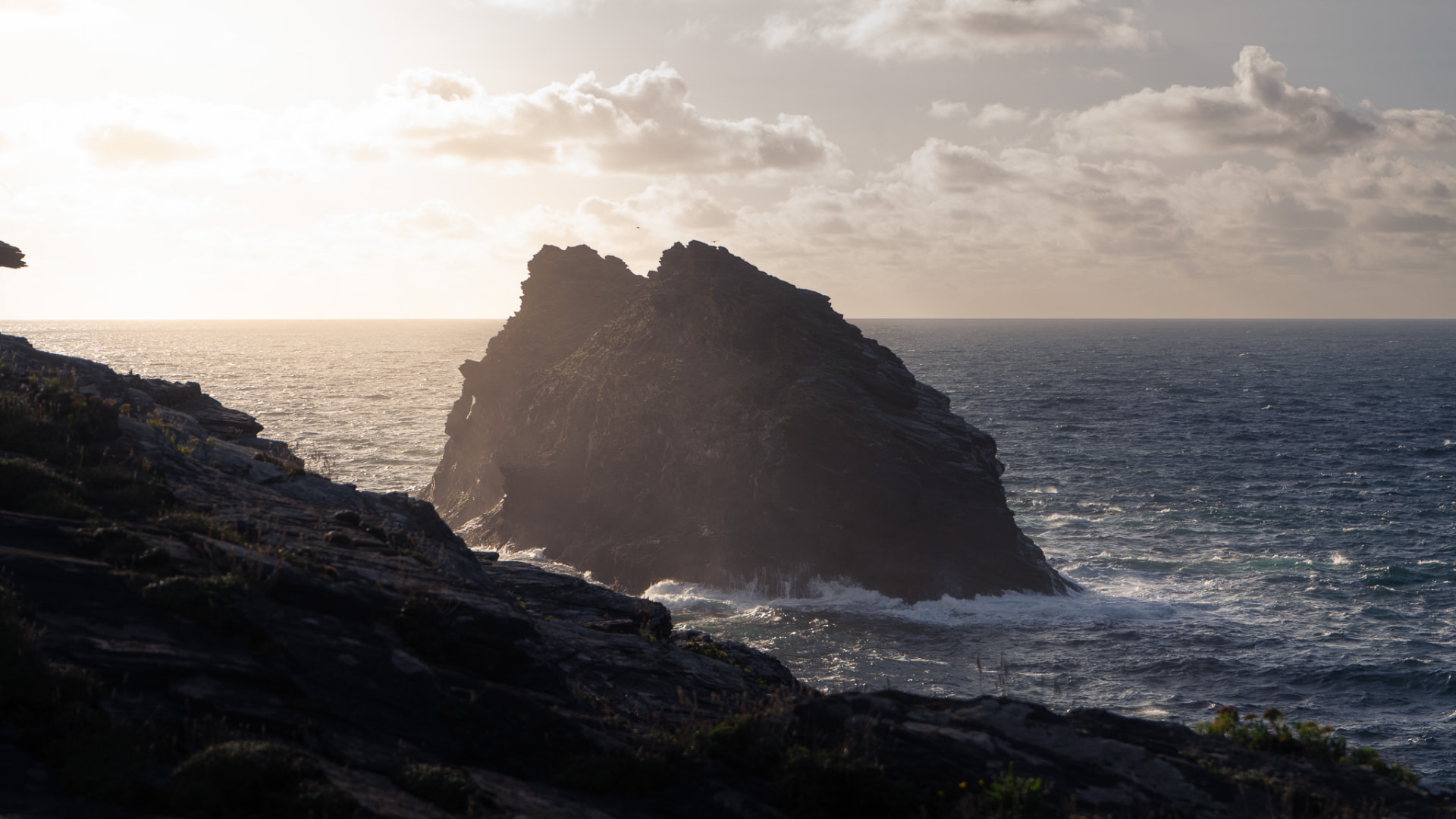 A rocky islet off the Cornish coast at Boscastle, silhouetted against the evening sun